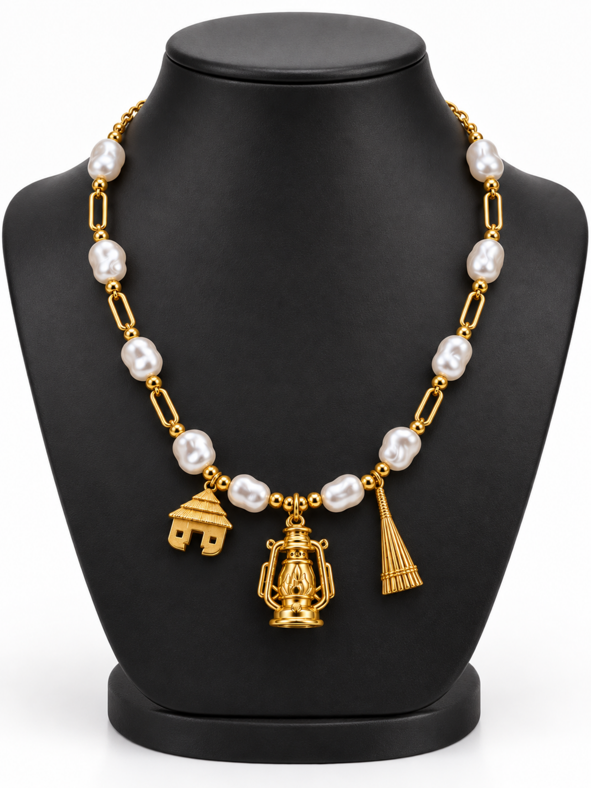 Villager Roots gold necklace with ten pearl-effect acrylic beads and hut, lantern and broom pendants, on a black display bust