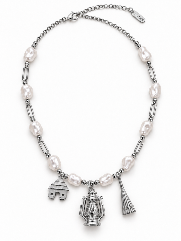 Villager Roots silver-colour necklace with ten pearl-effect acrylic beads and hut, lantern and broom pendants, on a white background